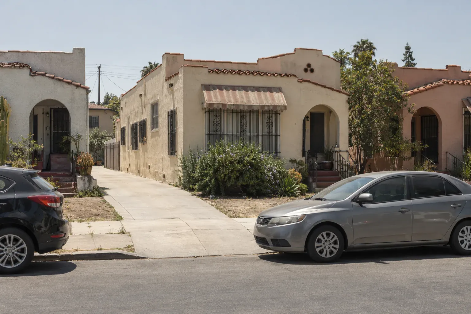 1920s Spanish-style duplexes with tile-trimmed flat roofs, typical of Mid-City