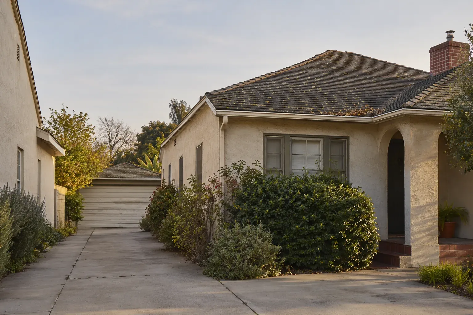 Older stucco home with a weathered asphalt shingle roof