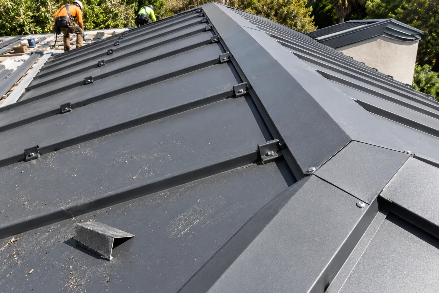 Close-up of standing-seam metal panels and a sealed pipe penetration